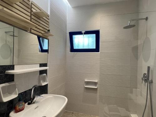a bathroom with a sink and a shower and a window at Maros Spitaki in Varípetron