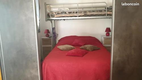 - un lit rouge avec deux oreillers dans une chambre dans l'établissement T2 luxe rdj cap d agde, au Cap d'Agde