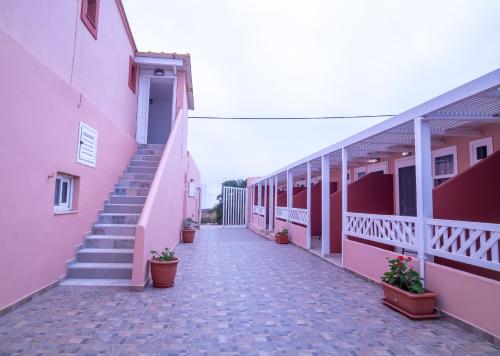 um corredor de edifícios cor-de-rosa com escadas e vasos de plantas em Ta Kymata Karpathos em Cárpatos