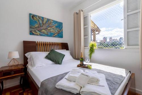 Un dormitorio con una cama y una ventana con una botella de vino en Casa aconchegante com 4 quartos na Vila Madalena en São Paulo