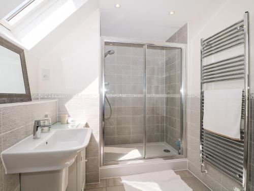 a bathroom with a shower and a sink and a mirror at Baldwin Close in Hook