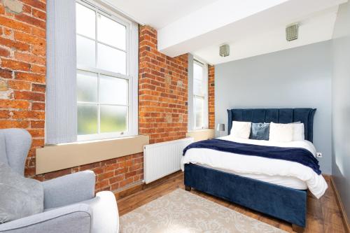 a bedroom with a bed and a brick wall at Au luxury apartment - free parking in Batley