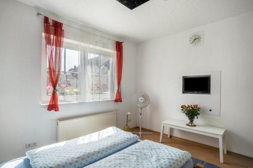 カッペル・グラーフェンハウゼンにあるFerienwohnung Schläferのベッドと赤いカーテンの窓がある寝室