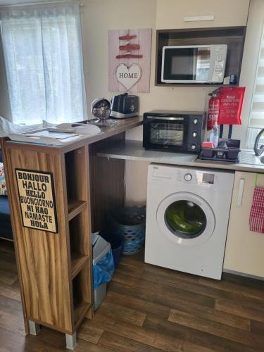 a kitchen with a washing machine and a microwave at Mobil home 6/8 pers Les Dunes de Contis in Saint-Julien-en-Born