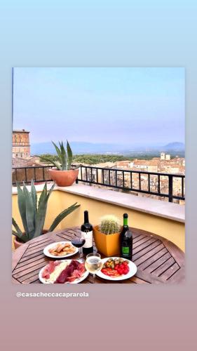 a table with two plates of food and wine on a balcony at Casa Checca e Casa Maria appartamenti per vacanze in Caprarola