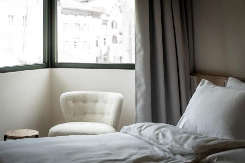 a bedroom with a bed and a chair and a window at ADLER Historic Guesthouse in Bressanone