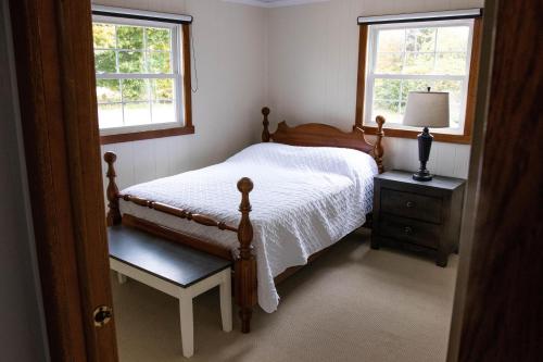 a bedroom with a bed and two windows at Tranquility Cottage 