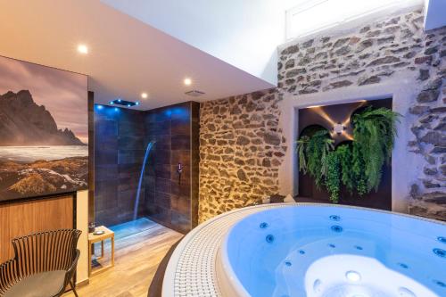 un baño grande con una gran bañera azul en Auberge de Clochemerle, Spa privatif & restaurant gastronomique, en Vaux-en-Beaujolais