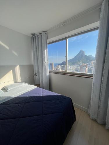 um quarto com uma cama e uma grande janela em Apartamento com Vista Imperdível no Rio de Janeiro