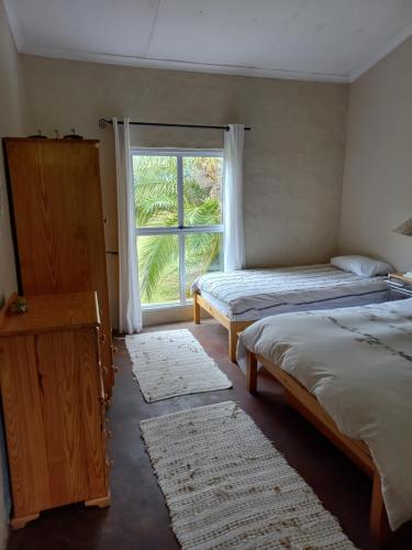 a bedroom with two beds and a window with rugs at Esperanza Countryside Accomodation in George