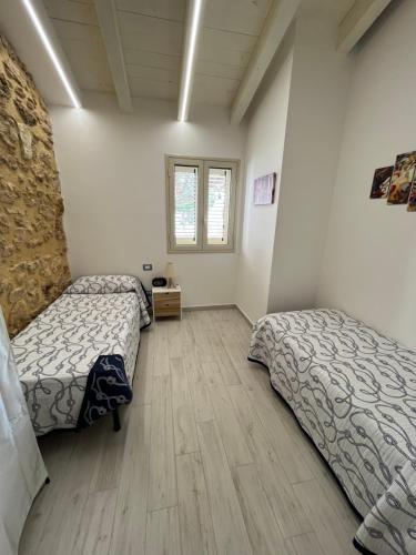 a bedroom with two beds and a wooden floor at Villa Sovareto in Sciacca