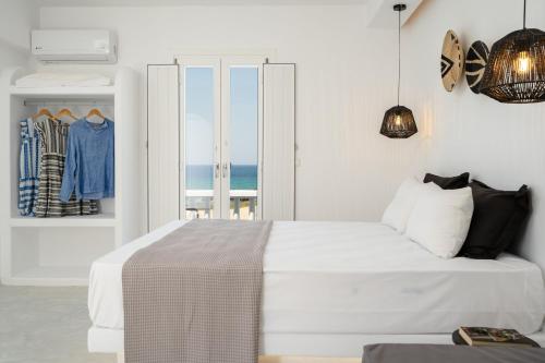 a white bedroom with a bed with a view of the ocean at Celestial Seaview Apartments-Portara in Naxos Chora