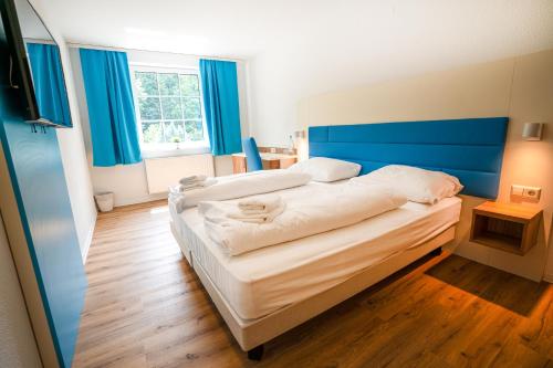 1 Schlafzimmer mit 2 Betten, blauen Wänden und Holzböden in der Unterkunft besttime Hotel Boppard in Boppard