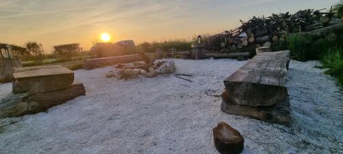 un gruppo di tronchi seduti sulla sabbia con il tramonto sullo sfondo di Yourte 4 personnes proche Provins et Disney a Bannost