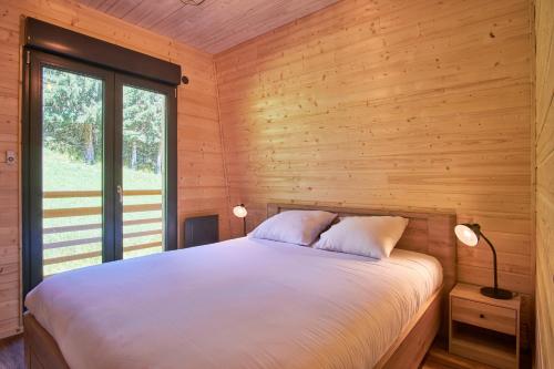a bedroom with a bed in a wooden cabin at Chalet le Lys Martagon in Saint-Pierre-dʼEntremont