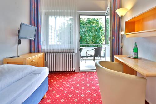 a hotel room with a bed and a desk and a balcony at Hotel am Park Bad Driburg in Bad Driburg
