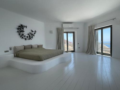 a white bedroom with a bed and large windows at Villa Faros in Fanari