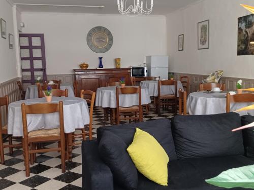 ein Wohnzimmer mit Tischen und einem Sofa in einem Restaurant in der Unterkunft Les Glycines in Le Vigan