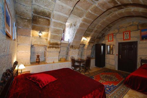 a bedroom with a red bed in a stone room at Karamanli Konagi in Guzelyurt