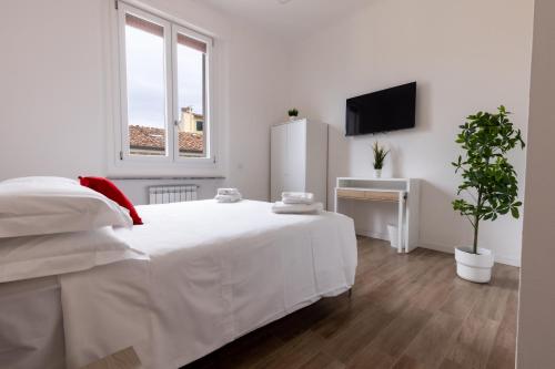 um quarto branco com uma cama branca e uma televisão em Cavour Florence Apartment em Florença