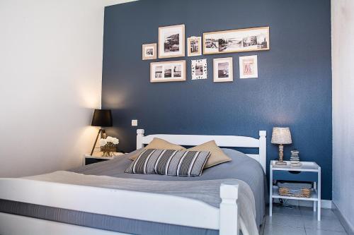 a bedroom with a white bed with a blue wall at Gîte classé 3 étoiles dans résidence standing avec - Piscine Clim Parking Wifi Prêt Vélos - Ménage et linge non inclus in Saint-Cyprien
