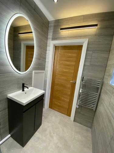 a bathroom with a sink and a mirror and a door at Walter Road Holiday Home Swansea - 4 bedrooms in Swansea