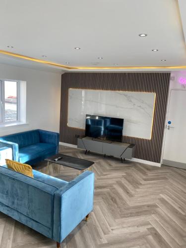 a living room with a blue couch and a tv at Walter Road Holiday Home Swansea - 4 bedrooms in Swansea