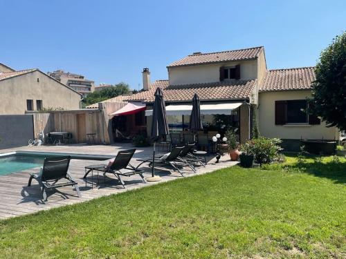 une terrasse avec des chaises et des parasols à côté d'une maison dans l'établissement Villa piscine, spa & pétanque à Uzès centre !, à Uzès
