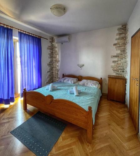 a bedroom with a wooden bed with blue curtains at Apartmani Mia in Palit