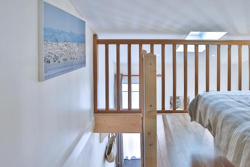 1 dormitorio con cama y barandilla de madera en Studio Le Petit Julien, en Saint-Julien-des-Landes