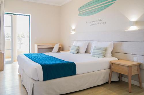 een slaapkamer met een groot wit bed met blauwe lakens bij Vitor's Plaza in Portimão