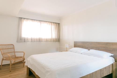 a bedroom with a bed and a chair and a window at Rodini House in Kato Rodini