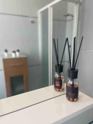 a bathroom counter with a mirror and two bottles with sticks at la casa di Alice in Vercelli