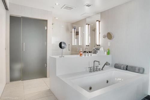 baño blanco con bañera grande y ducha en Luxury Well stocked SE Corner 2BR W Fort Lauderdale w Great Ocean Views en Fort Lauderdale