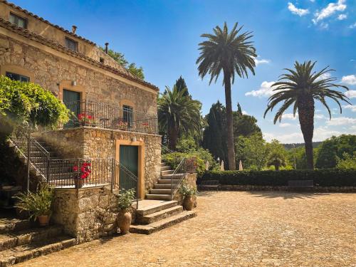 a stone building with stairs and palm trees in the background at Agriturismo Bannata in Piazza Armerina