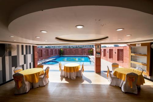 a room with two tables and a swimming pool at HOTEL ANAND INTERNATIONAL in Bodh Gaya