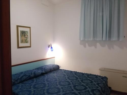ein Schlafzimmer mit einem Bett mit einer blauen Decke und einem Fenster in der Unterkunft Residence Oltremare in San Benedetto del Tronto