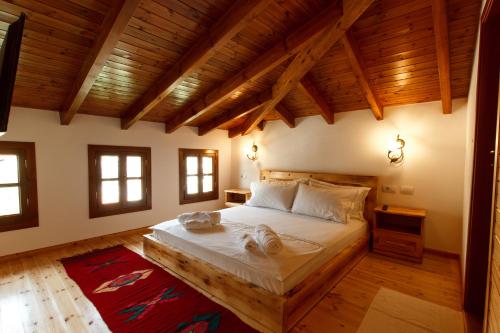 una camera con un grande letto in una stanza con soffitti in legno di Hotel Sarajet 1821 a Gjirokastër
