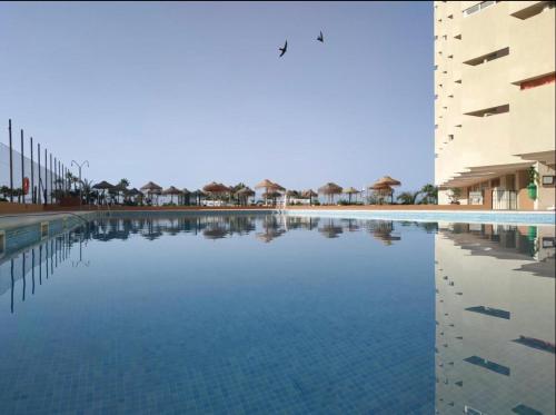 una gran piscina de agua frente a un edificio en Apartahotel CHINASOL con Parking y Desayuno, en Almuñécar