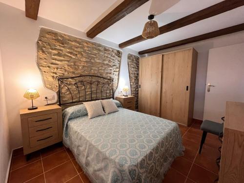 ein Schlafzimmer mit einem Bett und einer Steinmauer in der Unterkunft Ca la Beata in Cálig