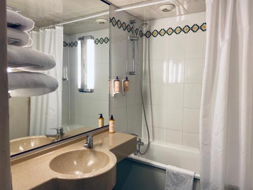 a bathroom with a sink and a mirror and a tub at Mercure Besancon Parc Micaud - Hotel & Bar in Besançon