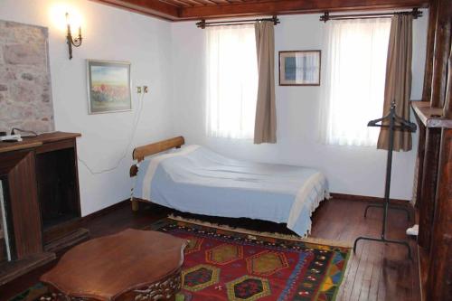 a bedroom with a bed and a table and windows at Cunda adasında rum evi in Ayvalık