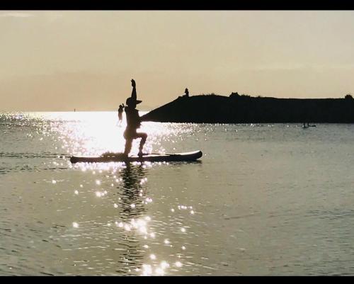 a person standing on a surfboard in the water at 心愈庭 in Itoman