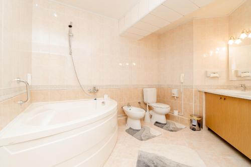 La salle de bains est pourvue d'une baignoire, de toilettes et d'un lavabo. dans l'établissement Dacia Hotel, à Chişinău