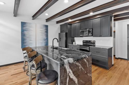 a kitchen with black cabinets and a counter with stools at McGregor & Main - Luxury Lofts in Hill City