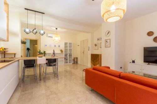 een woonkamer met een oranje bank en een keuken bij Sonnino House in Cagliari