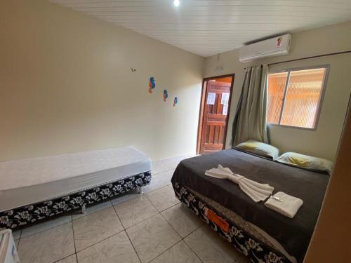 1 dormitorio con 2 camas y ventana en Pedra do Sol Pousada, en Alter do Chao