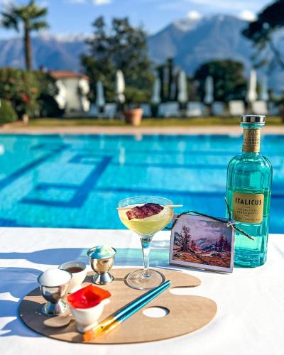 a bottle of wine and a drink on a table next to a pool at Parkhotel Delta, Wellbeing Resort in Ascona