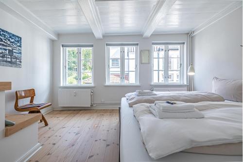 a white bedroom with two beds and a chair at Luettje Huus in Flensburg