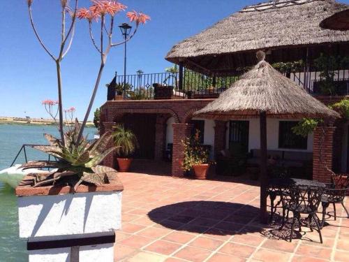 a house with a thatch roof and a table and chairs at Espectacular casa con embarcadero in Arcos de la Frontera